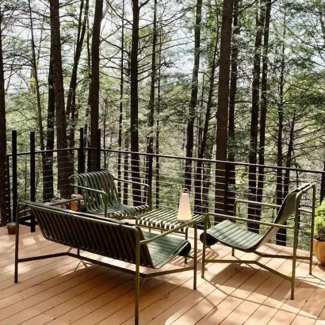Chic green outdoor furniture overlooks the woods