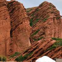 The dramatic diagonal structures of the red-rock Jety-Oguz canyon, Kyrgyzstan, with a jeep and white yurt