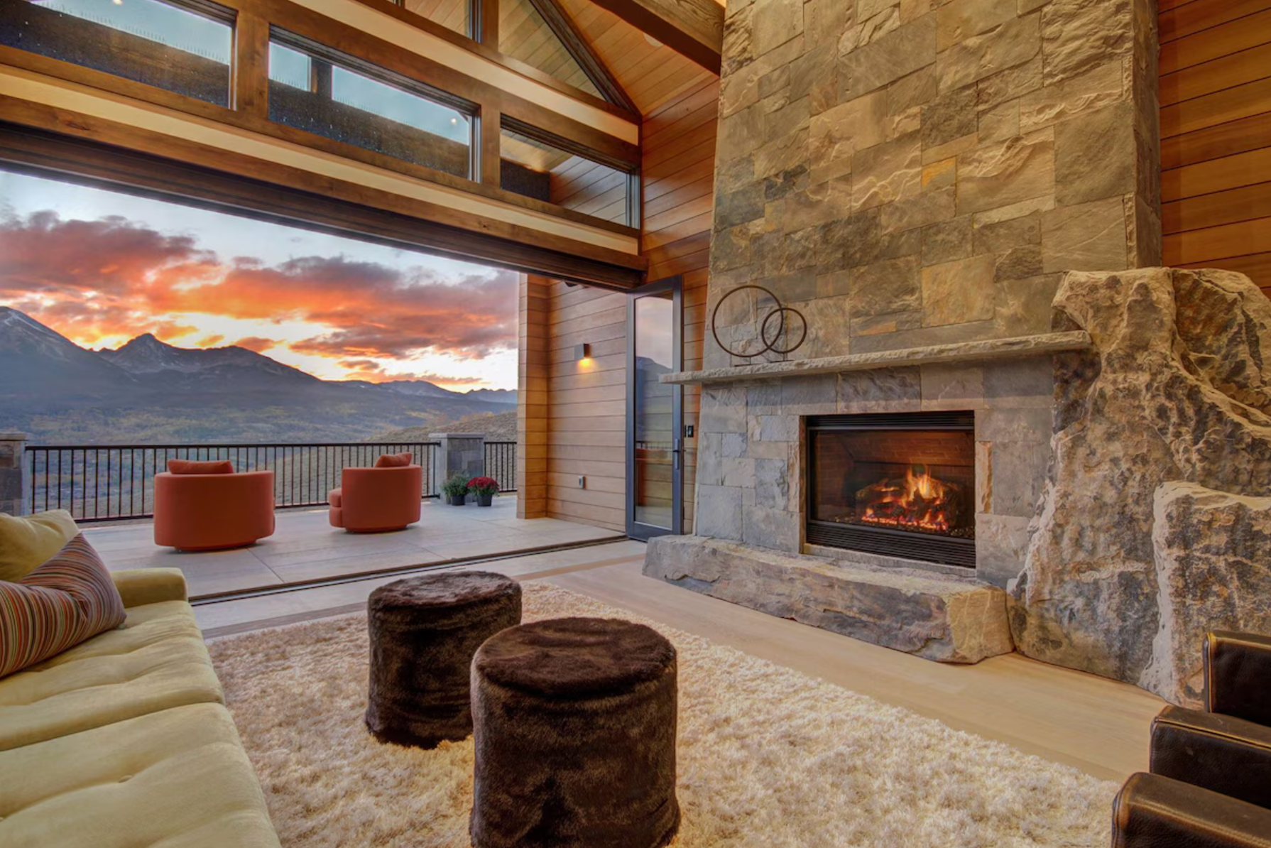 The lounge area with fireplace and chairs out on the terrace overlooking the mountains at sunset at a Vrbo rental property in Silverthorne, Colorado