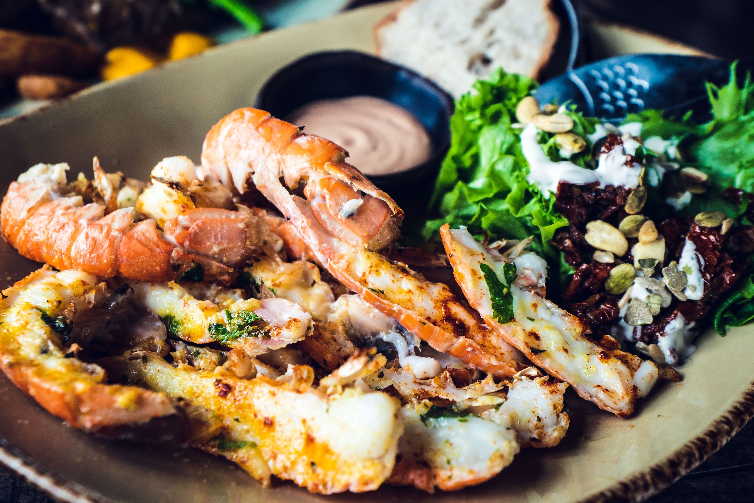 A close-up of several cooked langoustines arranged on a plate with their shells and claws visible.
