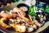 A close-up of several cooked langoustines arranged on a plate with their shells and claws visible.