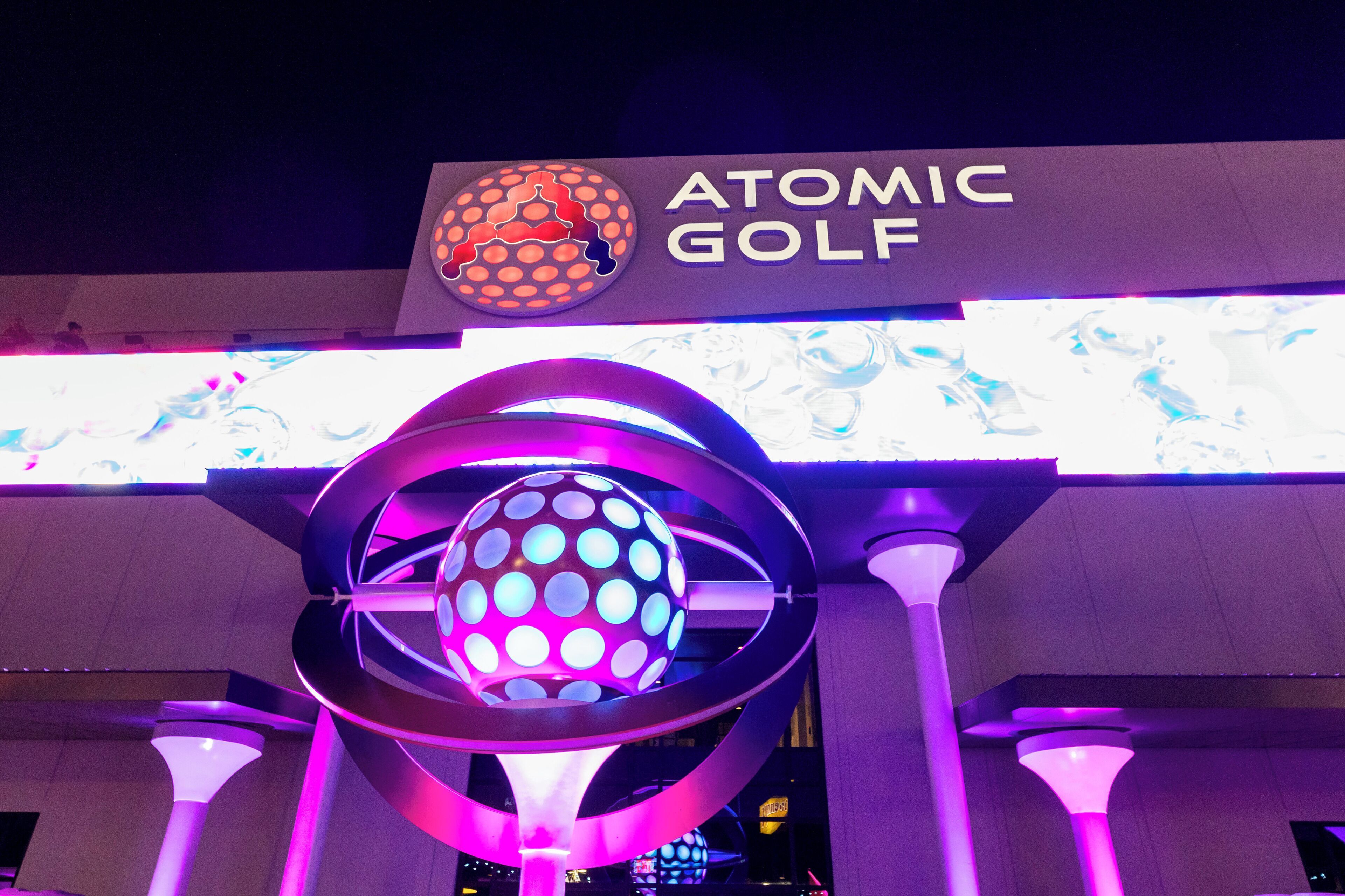 The purple neon-lit exterior of Atomic Golf at The STRAT Hotel in Las Vegas, Nevada