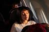 A woman sitting on an airplane closes her eyes peacefully