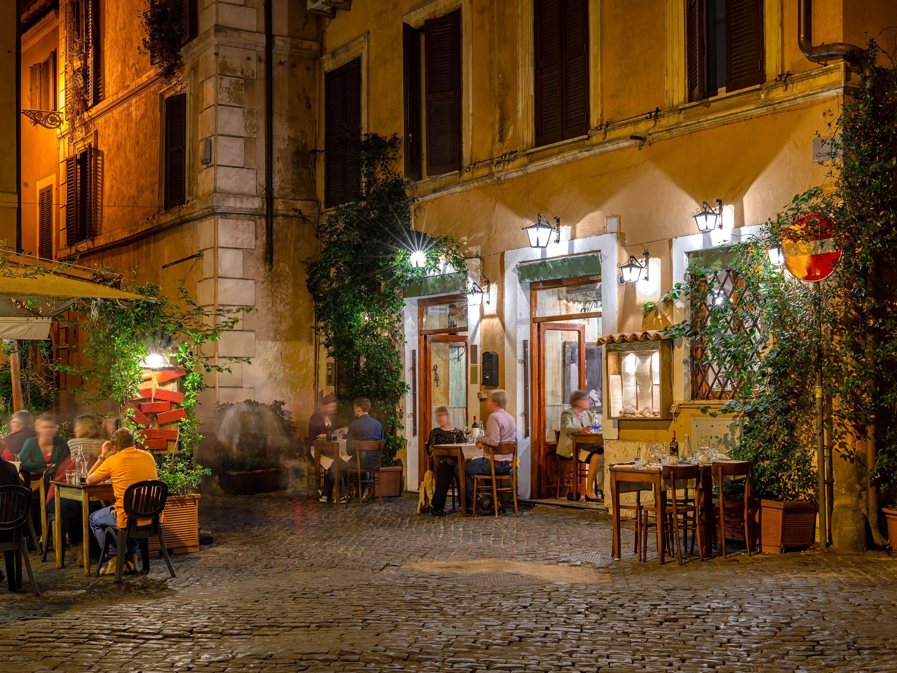 Cobblestone plaza with restaurants and outdoor tables.