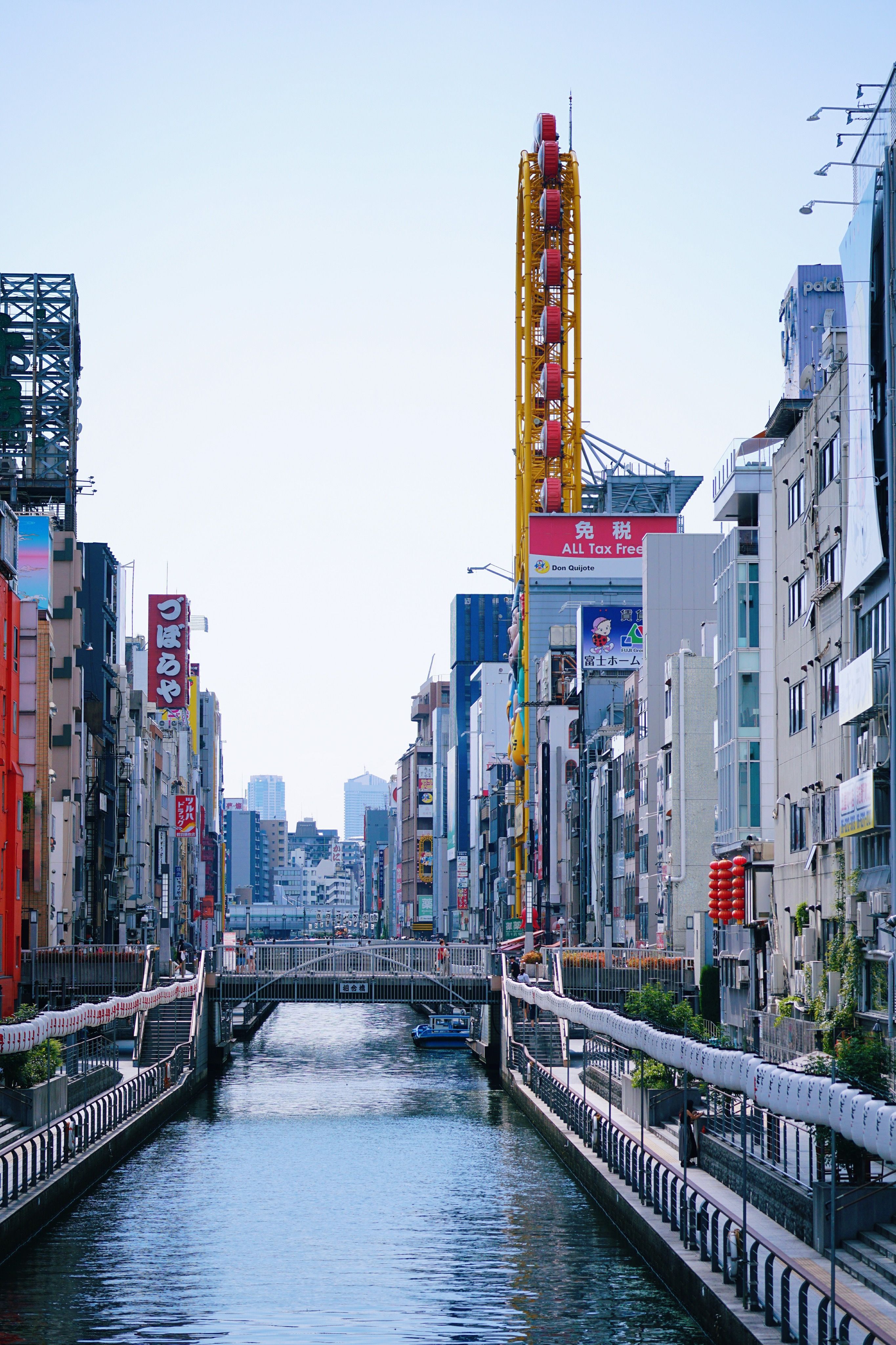 The Dōtonbori canal is lined by tall, colorful buildings on a clear day in Osaka, Japan