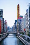 The Dōtonbori canal is lined by tall, colorful buildings on a clear day in Osaka, Japan