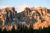 Italian dolomite mountain peaks with scattered snow reach into the clouds.