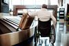 Person in a wheelchair retrieves their luggage from a carrousel.