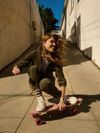 Sierra Prescott crouches on a pink skateboard at the bottom of a slope, her long hair blowing in the wind