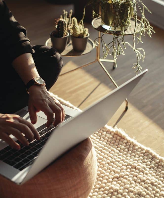 Hands seen working on a laptop on a sunny porch