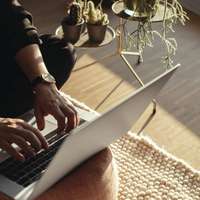 Hands seen working on a laptop on a sunny porch