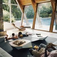 Two children play a game in a light filled Vrbo, with a view onto a pool