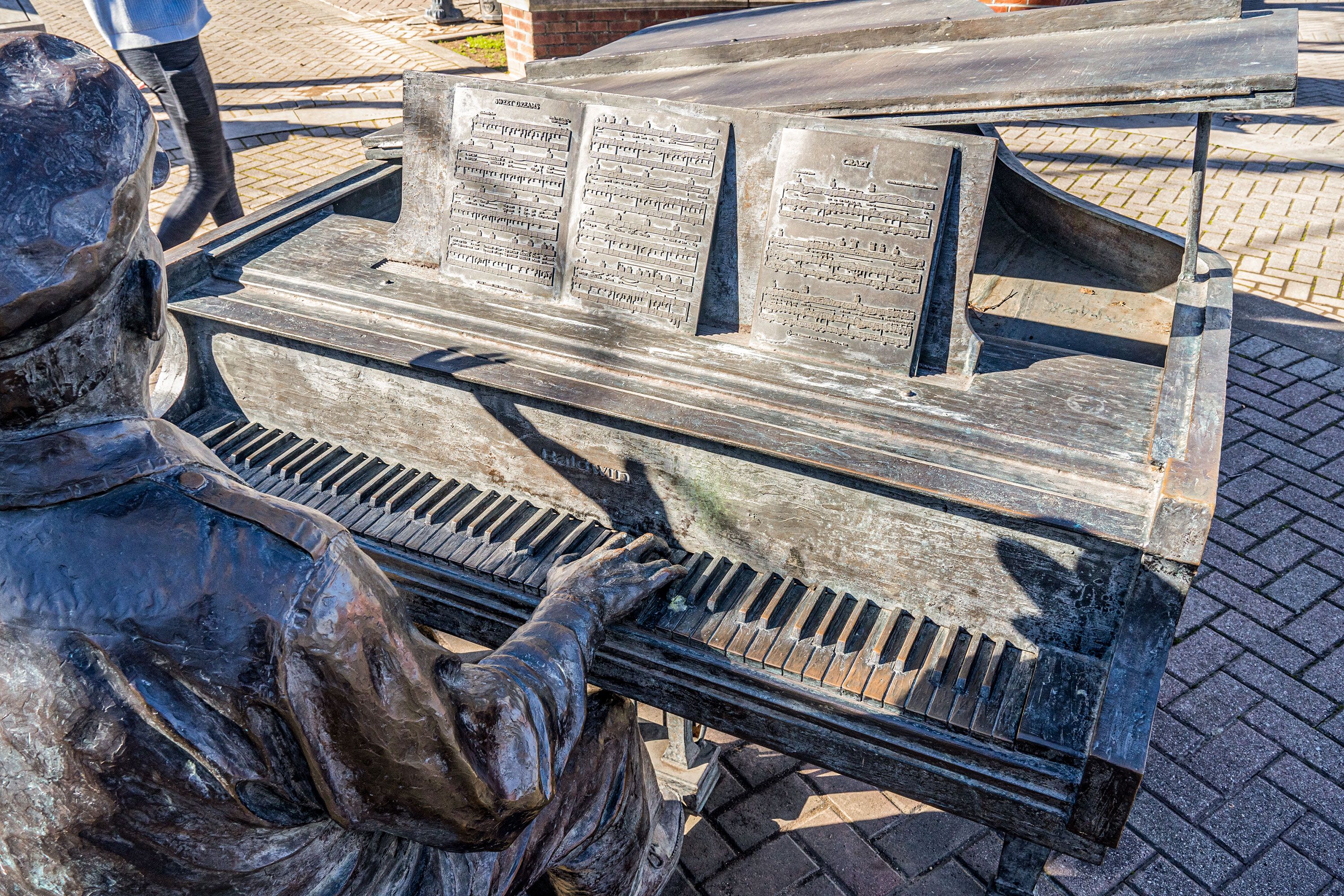 Over the shoulder view of outdoor full size sculpture of piano player with sheet music.