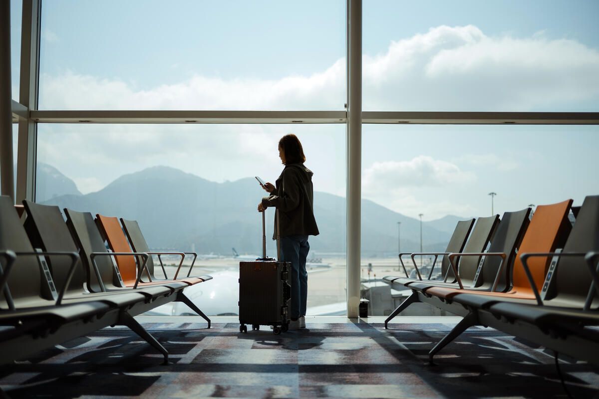 A woman on her phone waiting for a flight in an airport. 