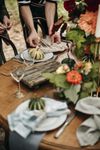 A rustic wooden table set with linen napkins, miniature pumpkins, and potted plants