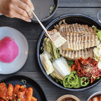 A person holding chopsticks picks a slice of tofu from a large bowl of brightly colored vegetarian food at Hangari in Koreatown, Los Angeles