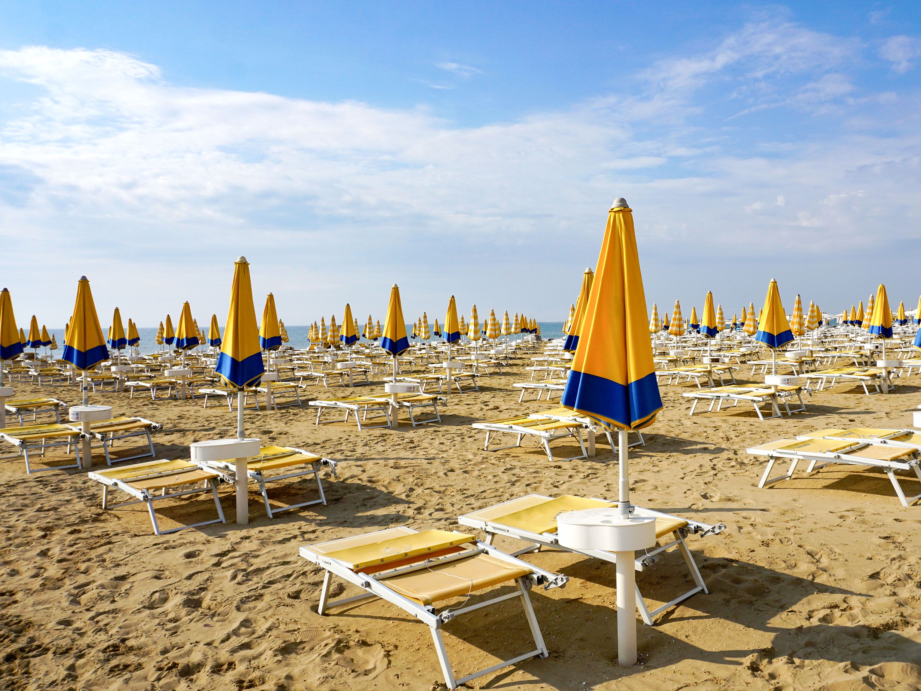 Yellow beach chairs and yellow and blue umbrellas on the beach.