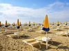 Yellow beach chairs and yellow and blue umbrellas on the beach.
