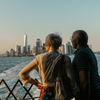 A man and woman look out over the Hudson to New York City's skyline in the distance