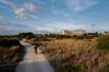 A man drives a motor scooter towards Selinunte, ancient Greek ruin in Sicily, Italy