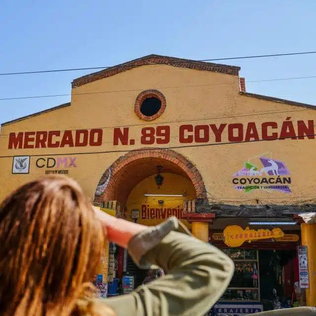 A person seen from behind looks up at the colorful Coyoacàn Market in Mexico City