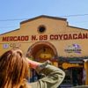 A person seen from behind looks up at the colorful Coyoacàn Market in Mexico City