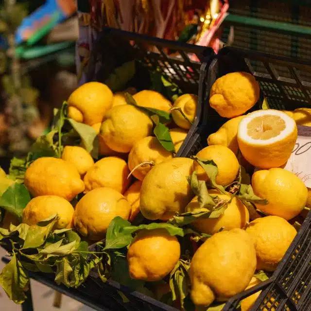 Fresh, bright yellow lemons are piled up in a crate at a market in Italy