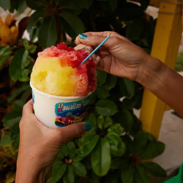 A paper tub piled high with bright yellow and red shave ice