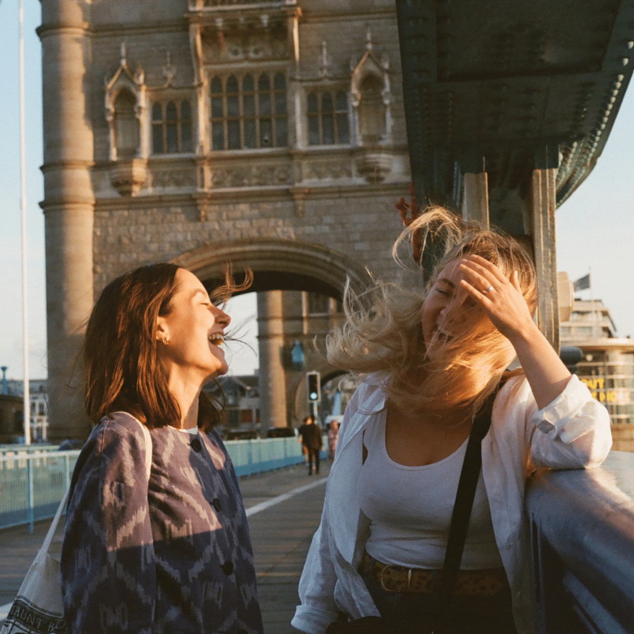 Two women laugh on Tower Bridge in London, England