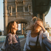 Two women laugh on Tower Bridge in London, England
