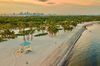A sunset on the beach of Key Biscayne with palm trees and the buildings of Miami in the background.
