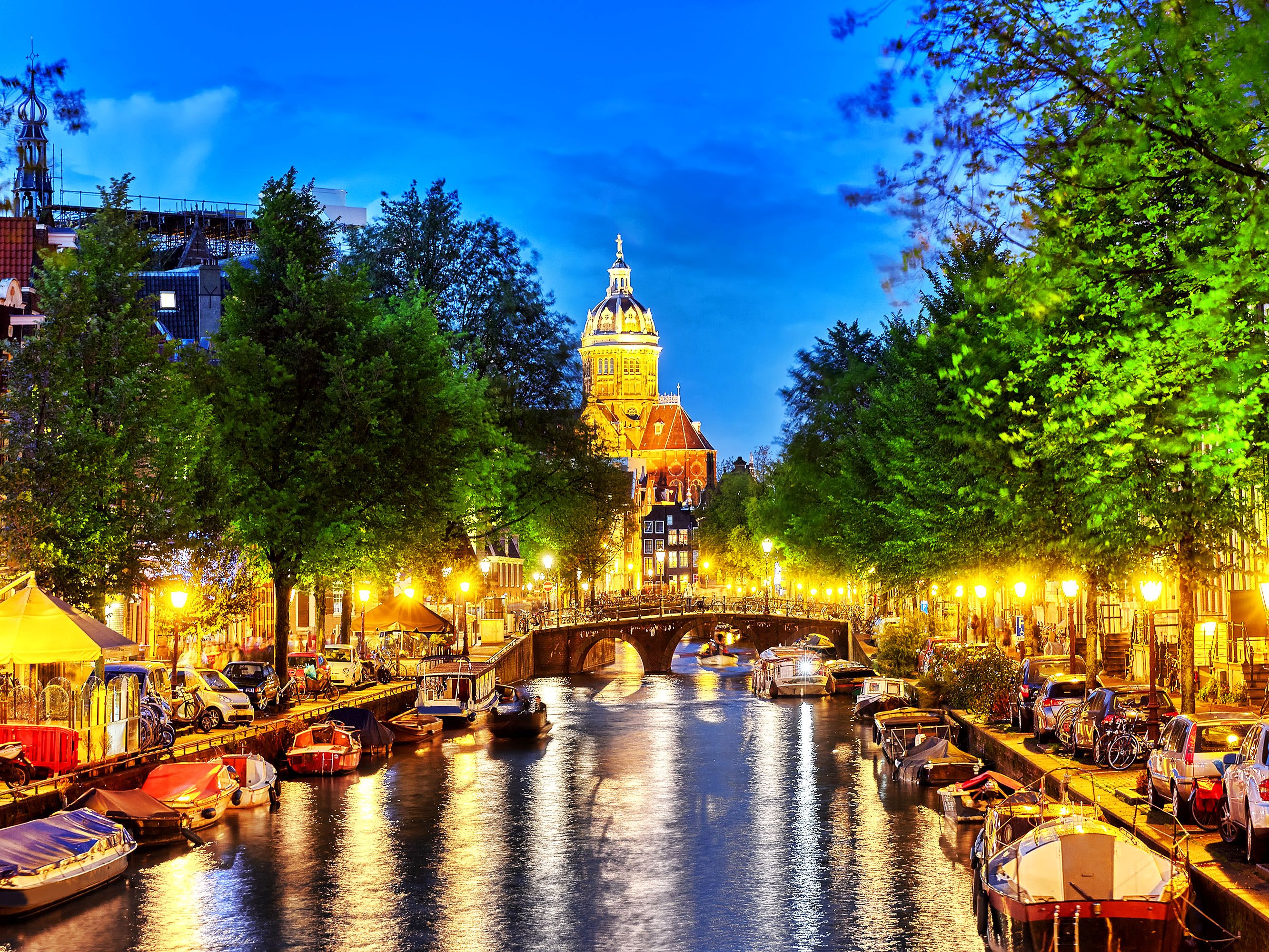 Night view of canal with boats tied up and a stone bridge.