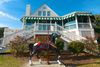 A carousel horse displayed in front of a white coastal house with green-and-white awnings.