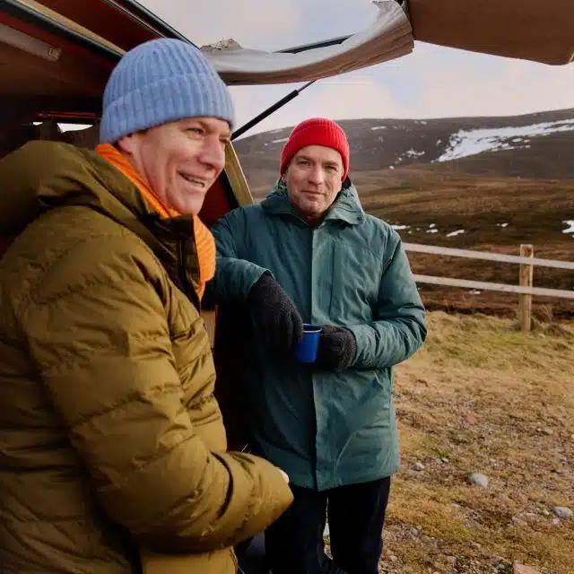 Wrapped up against the cold and sheltered by their campervan in the Scottish Highlands, brothers Colin McGregor and Ewan McGregor have a cup of warming soup