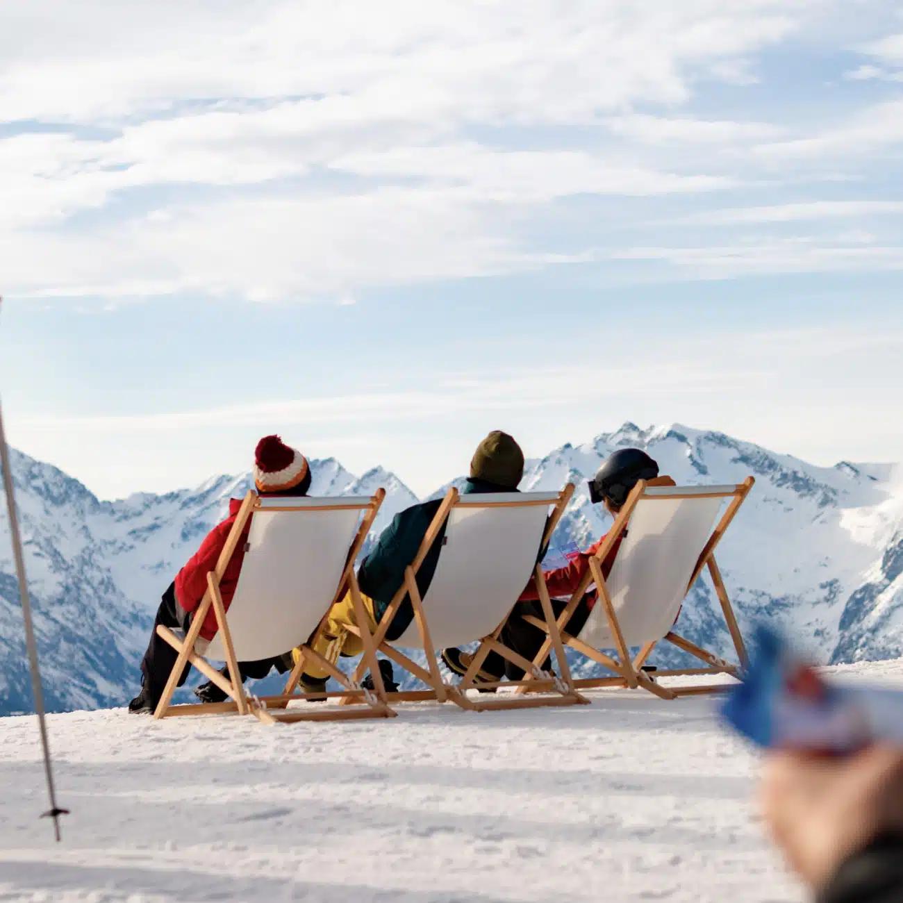 People recline on deckchairs atop a mountain on a sunny day in the French Alps