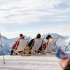 People recline on deckchairs atop a mountain on a sunny day in the French Alps