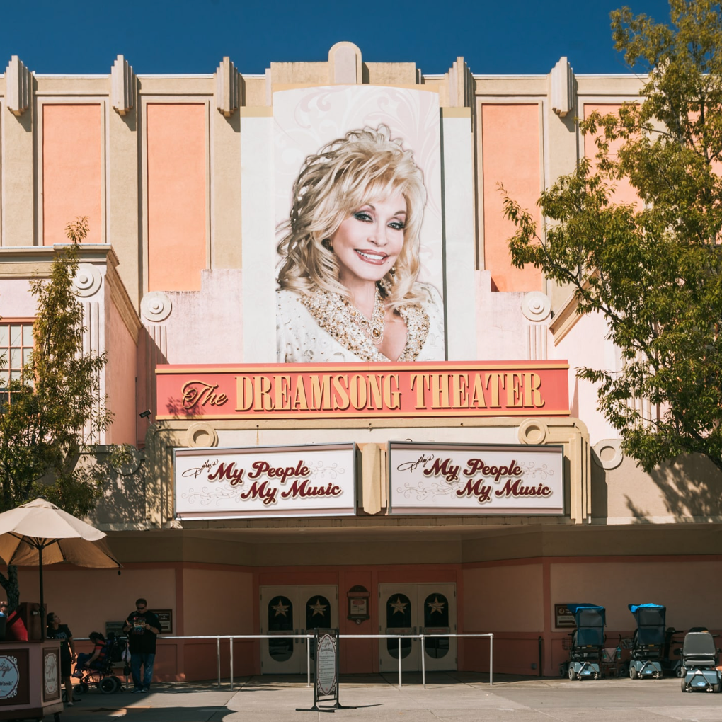 A large image of Dolly Parton smiling on the pink exterior of The Dreamsong Theatre
