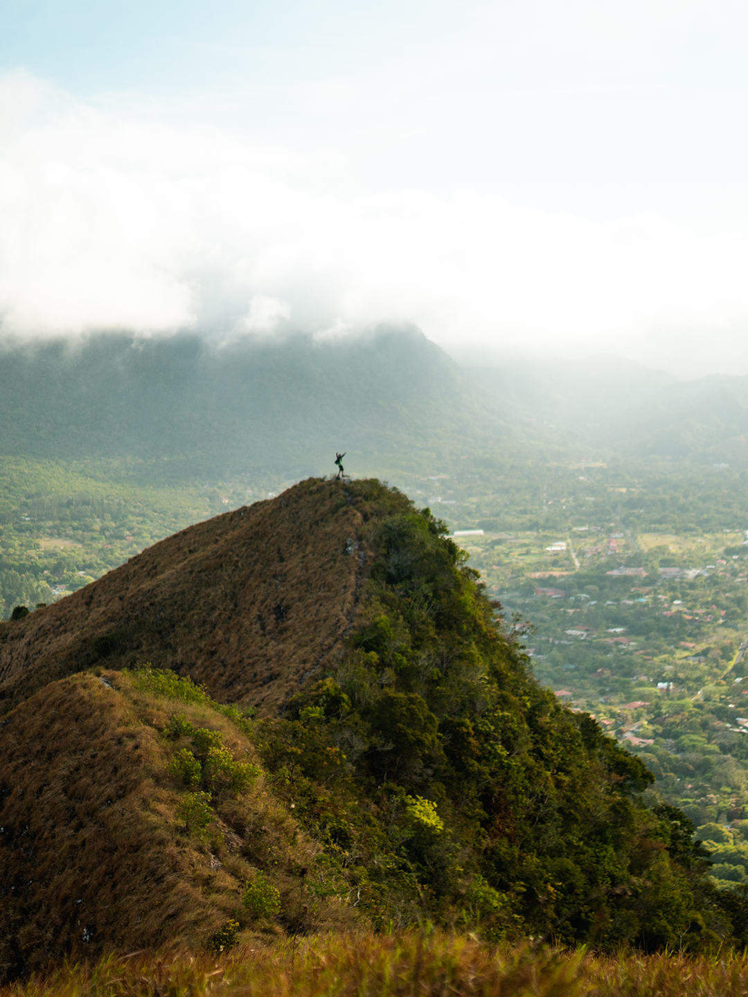 A person stands on top of a hill overlooking green countryside in Panama