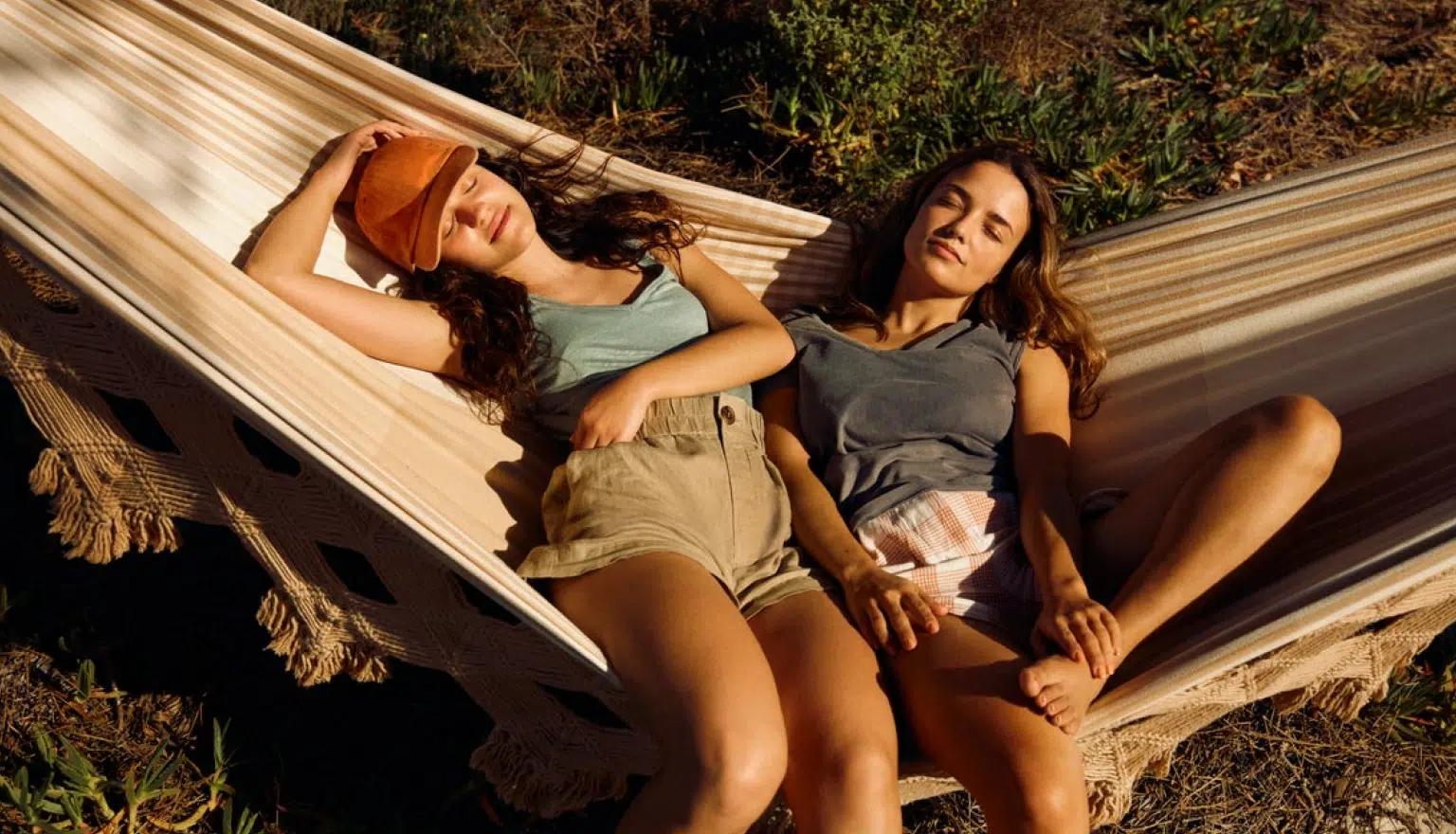Two women relaxing in the sun on a hammock