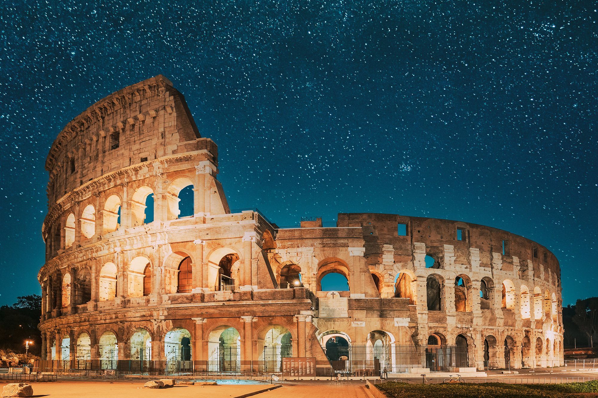 The Colosseum in Rome during nighttime with stars in the sky.