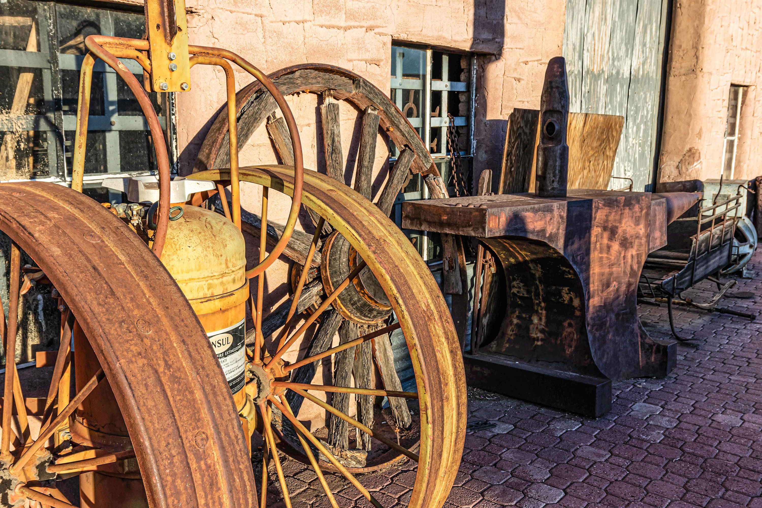 Old wooden fire fighting equipment with wagon wheels on stone tile ground against old building.