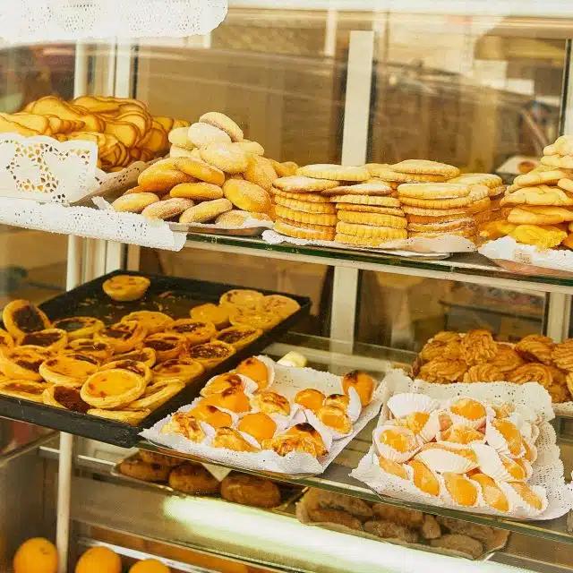 A shop window displaying Portuguese baked goods, including cookies, cakes and pasteis de nata