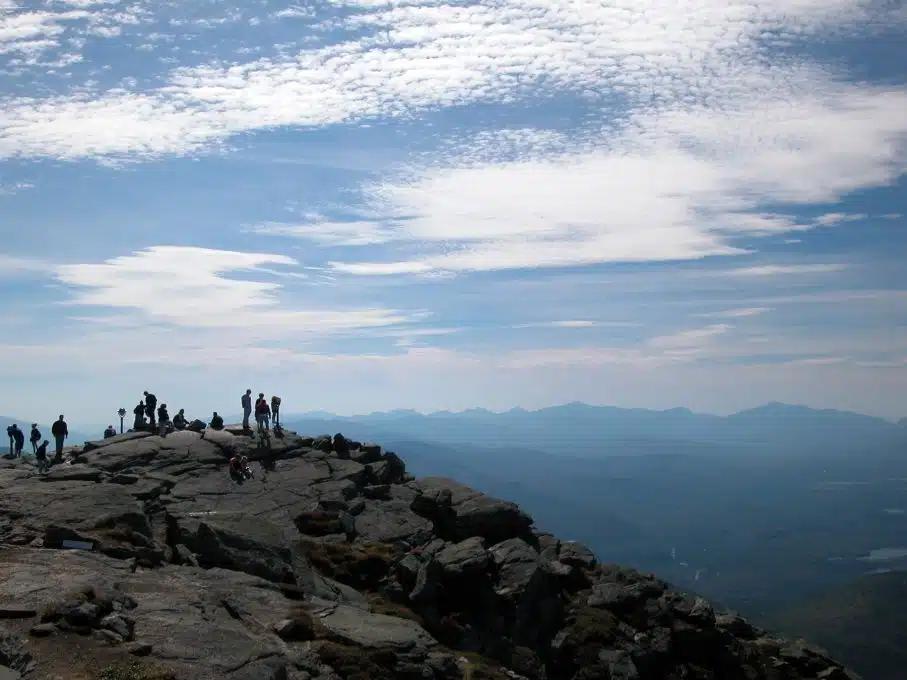 People stand at the top of a peak in the Adirondack Mountains