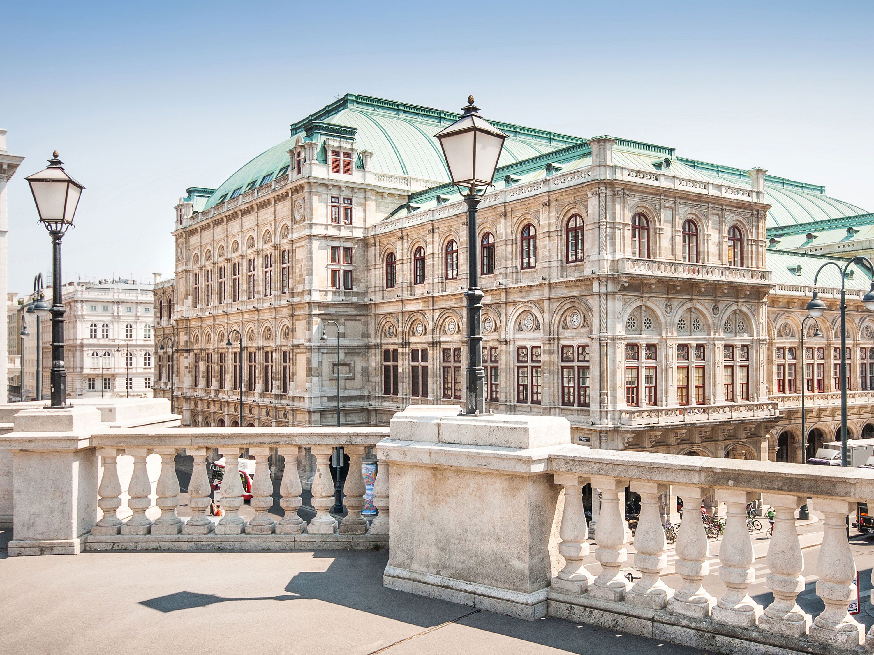 Vienna State Opera viewed from a white stone platform with lampposts in the foreground