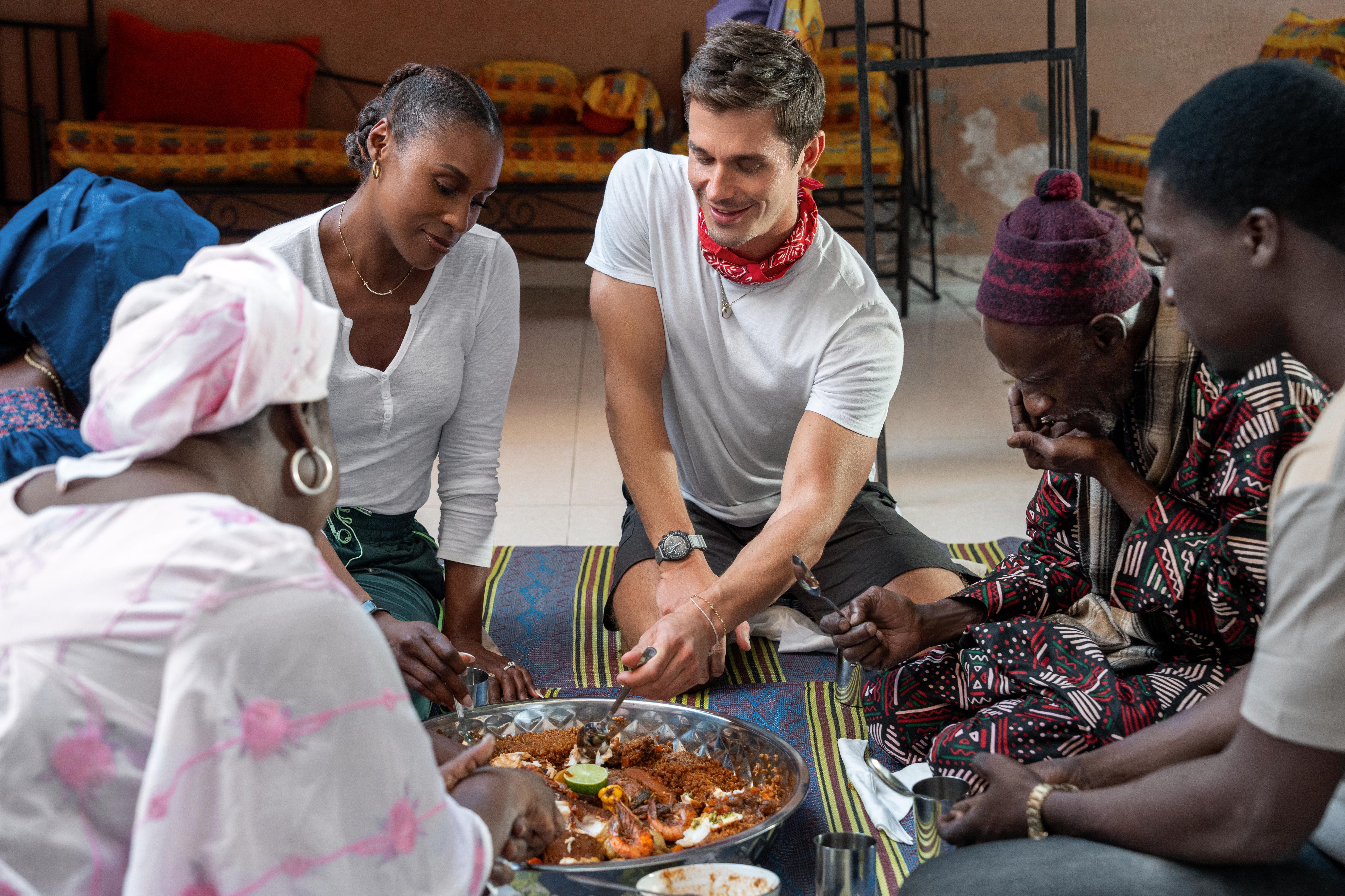 Issa Rae and Antoni Porowski sit to eat with a group in the Nat Geo series No Taste Like Home