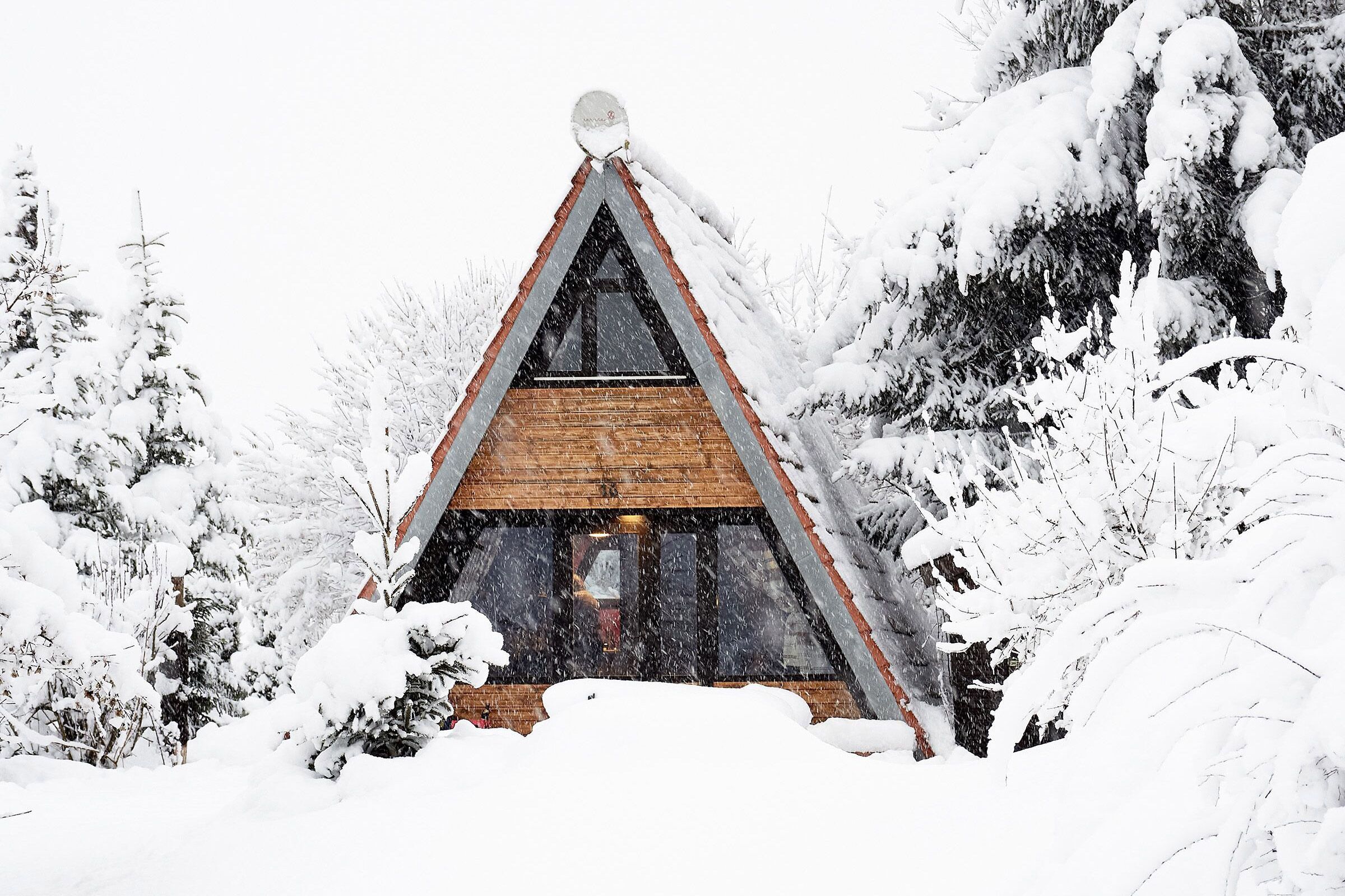 Ein eingeschneites Nur-Dach-Haus oder A-Frame in einem Winterwald
