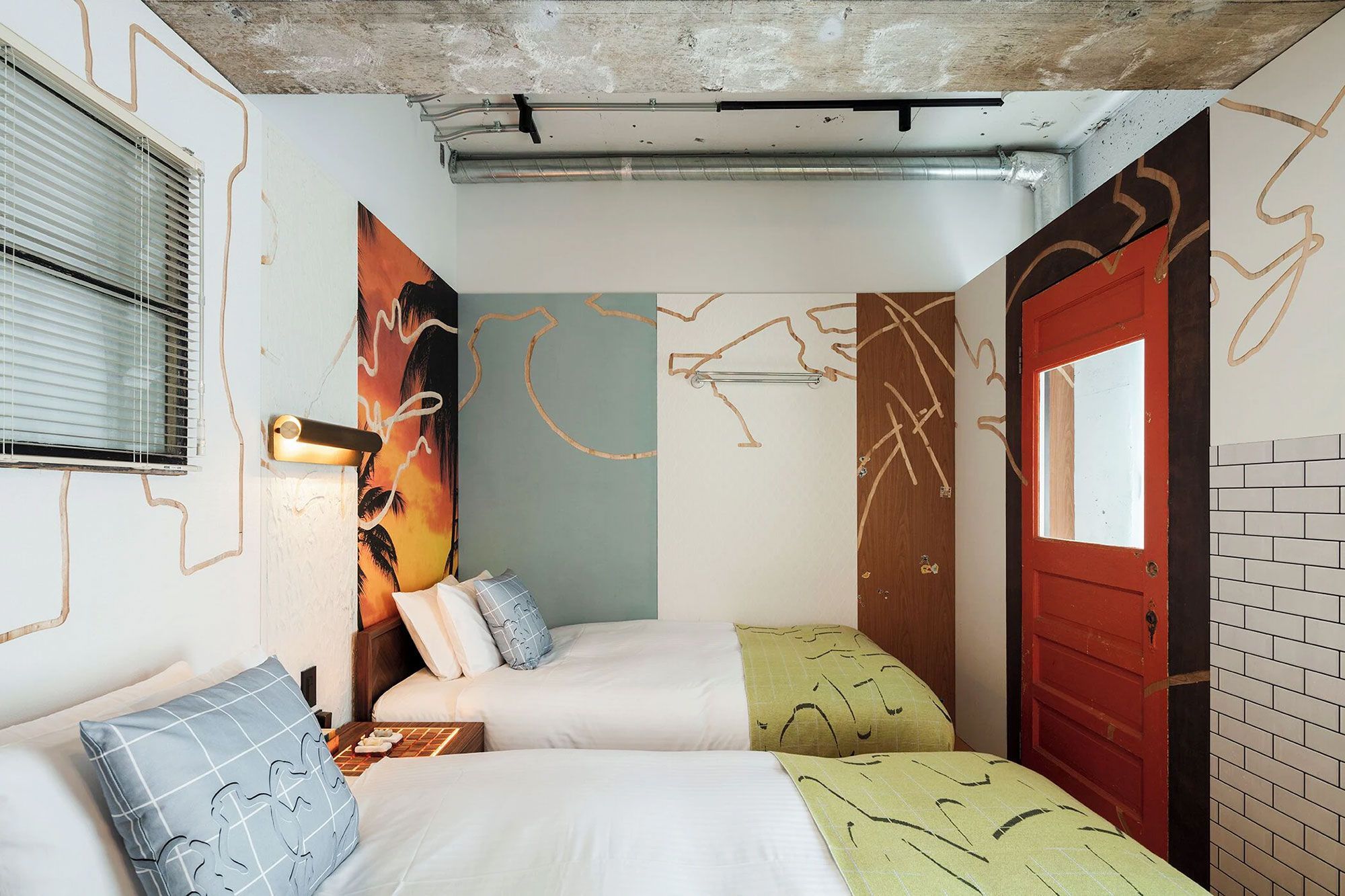 A small room with two smalls beds in the foreground and different colored wall behind.