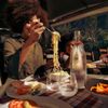 A young person is eating spaghetti in a restaurant in Rome, Italy, holding a forkful of noodles up from the bowl