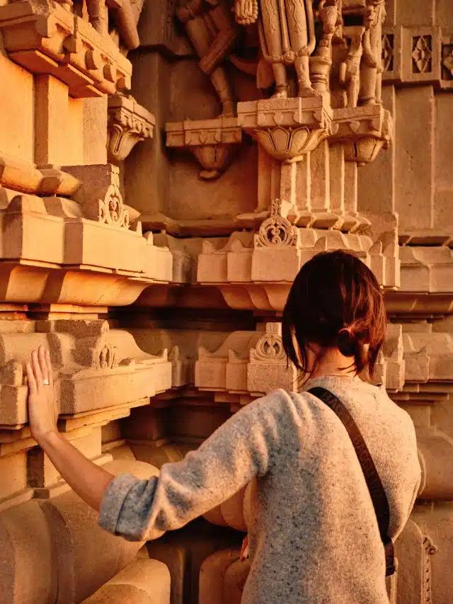 A woman is seen from behind admiring ruins at Mandore Garden, Jodphur, India, at sunset
