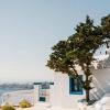 A whitewashed house with bright blue window frames on a hillside in Santorini
